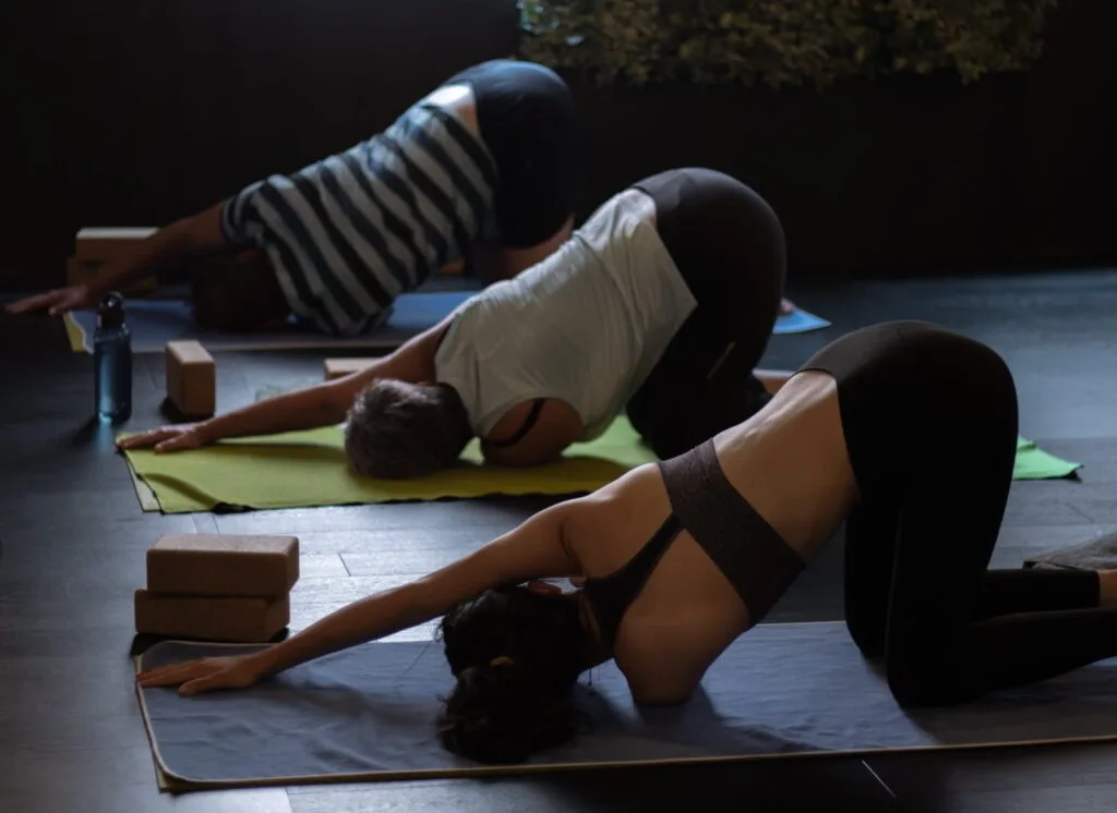 Drie yogi's doen een yoga houding in zaal twee bij Spirit of Yoga